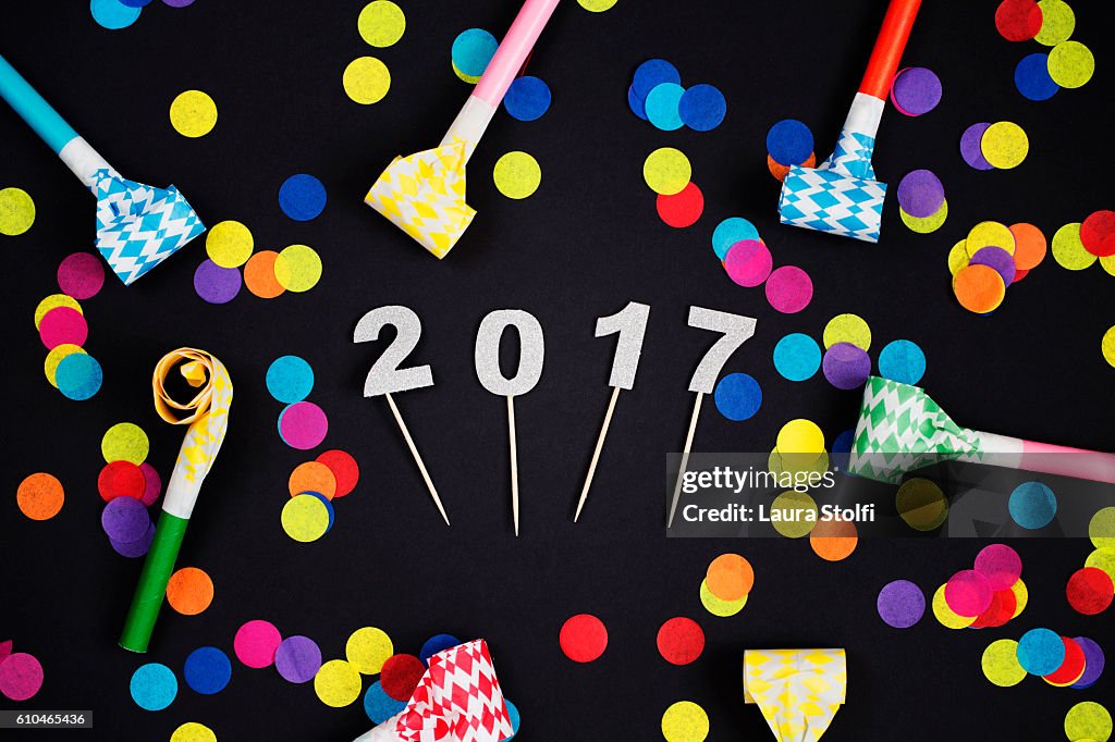 Glittery 2017 numbers amongst colorful confetti and party horns