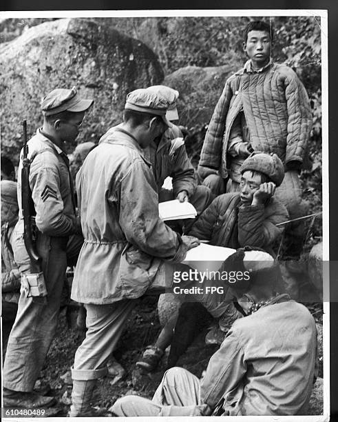 Marines with their Chinese prisoners at Chosin Reservoir in Changjin County, North Korea, during the Korean War, 1950. Here Marine Technical Sergeant...