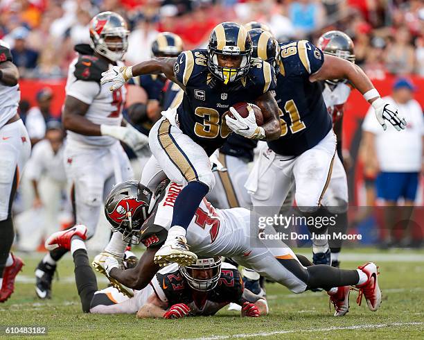 Runningback Todd Gurley of the Los Angeles Rams jumps over Safety Chris Conte and Strong Safety Keith Tandy a running play during the game against...