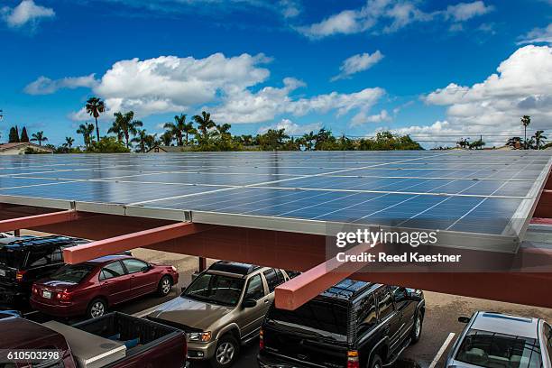solar panels mounted above a parking area supply electricity for a business and shade for the cars below. - disco de energía solar fotografías e imágenes de stock