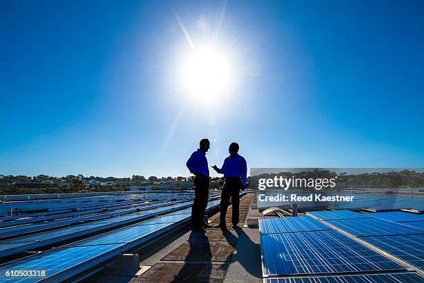 two men discuss the solar system on the roof of a commercial building. - solar energy dish 個照片及圖片檔