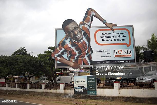 An advertisement for Bond online banking sits above a parking lot in Accra, Ghana, on Tuesday, Sept. 20, 2016. Ghana's central bank expects mergers...