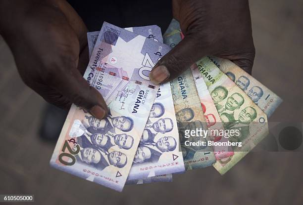 Man holds a collection of Ghana cedi banknotes in Accra, Ghana, on Tuesday, Sept. 20, 2016. Ghana's central bank expects mergers and acquisitions...