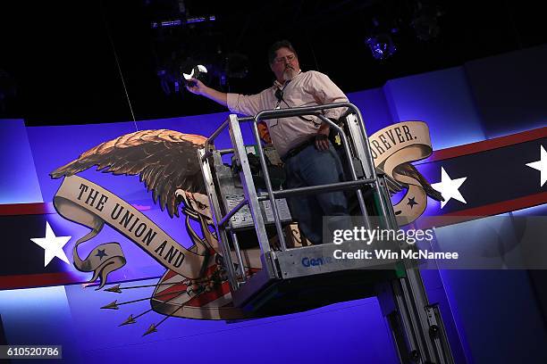 Member of the production team adjusts the lights on the stage for Monday night's presidential debate between Democratic presidential candidate...