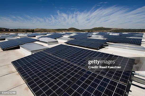 an array of solar panels mounted on the roof of a commercial building help reduce energy costs. - disco de energía solar fotografías e imágenes de stock