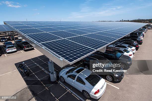 solar panels mounted above a parking area supply electricity for a business and shade for the cars below. - car sunshade stock pictures, royalty-free photos & images