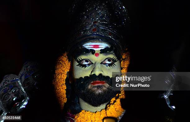 An indian artist ,dressed as an hindu's mythological evil King 'Ravan' , applies make up before a religious procession ' Ravan Barat ' in the old...