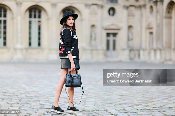 Sarah Benziane , is wearing a black hat, a New Look black bombers jacket with colored features and the word "L'Amour" written, a Bershka pink top, a...