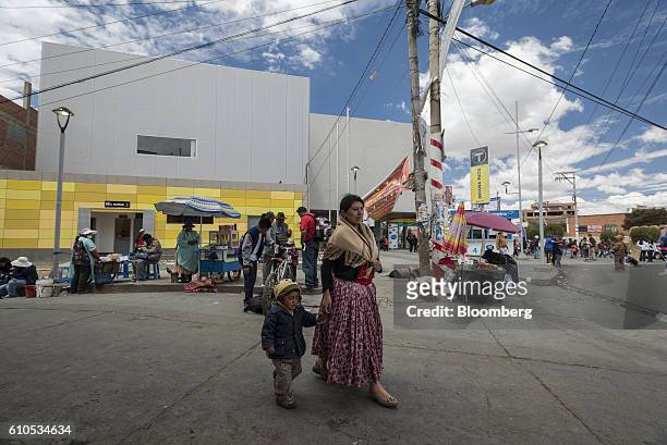 An Aymara woman dressed in traditional clothes walks outside the yellow line Mi Teleferico cable car station in El Alto, Bolivia, on Sunday, Sept. 4,...