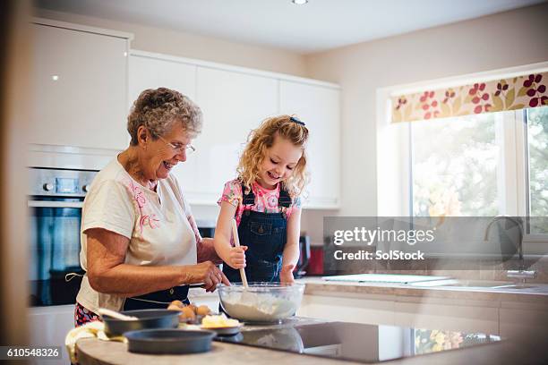 baking a cake with grandma - granddaughter stock pictures, royalty-free photos & images