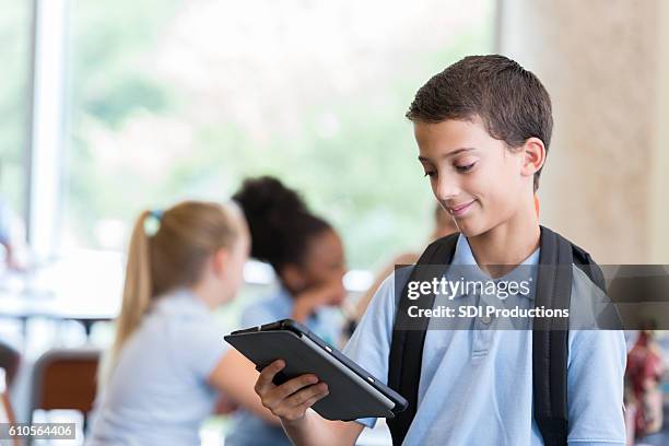 schoolboy looks at something on digital tablet - charter school stock pictures, royalty-free photos & images