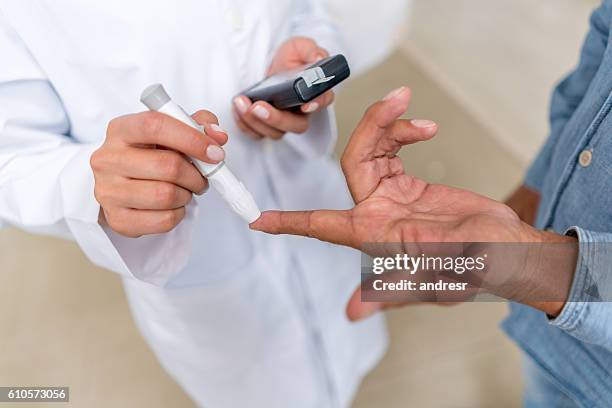 man checking sugar level with glucometer - glucose stockfoto's en -beelden