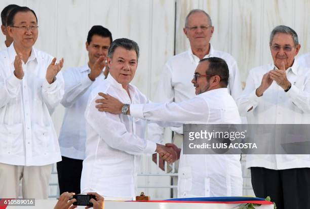 Colombian President Juan Manuel Santos and the head of the FARC guerrilla Timoleon Jimenez, aka Timochenko, shake hands during the signing of the...