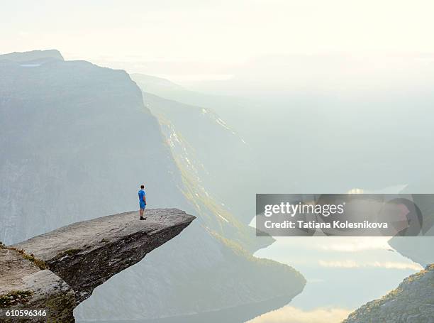 hiker standing on trolltunga - steilküste stock-fotos und bilder