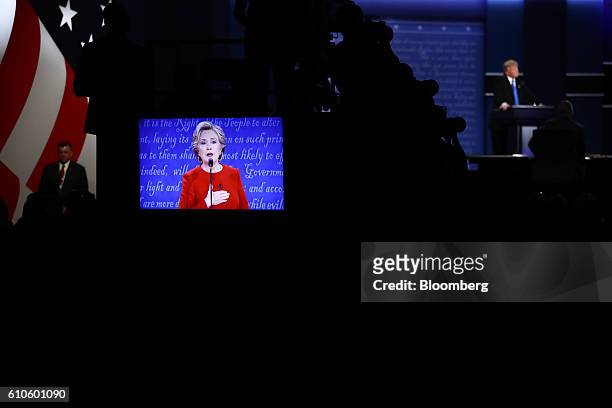 Hillary Clinton, 2016 Democratic presidential nominee, is seen speaking on a screen as Donald Trump, 2016 Republican presidential nominee, stands on...