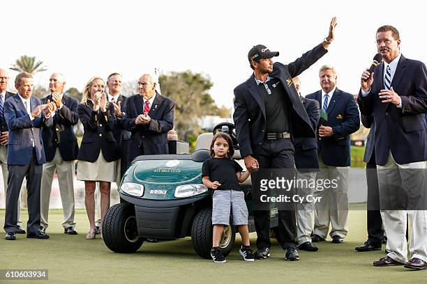 Jason Day of Australia, with his son Dash, waves to fans during a trophy ceremony following his one stroke victory on the 18th hole green in the...