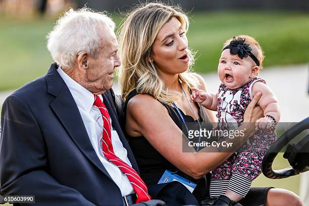 Arnold Palmer sits with Ellie Day, wife of Jason Day of Australia, and their daughter Lucy Day, following Jason's trophy ceremony on the 18th hole...
