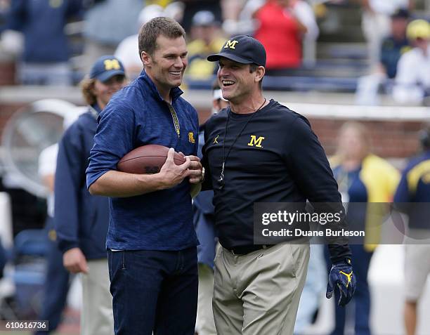 Quarterback Tom Brady of the New England Patriots laughs with head coach Jim Harbaugh of the Michigan Wolverines after they played catch before a...