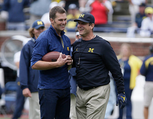 Quarterback Tom Brady of the New England Patriots laughs with head coach Jim Harbaugh of the Michigan Wolverines after they played catch before a...