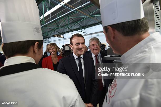 Former French Economy Minister and founder of the political movement "En Marche" Emmanuel Macron speaks with a chef as Besancon mayor Jean-Louis...