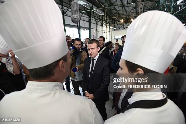 Former French Economy Minister and founder of the political movement "En Marche" Emmanuel Macron speaks with a chef during a visit to the cooking...