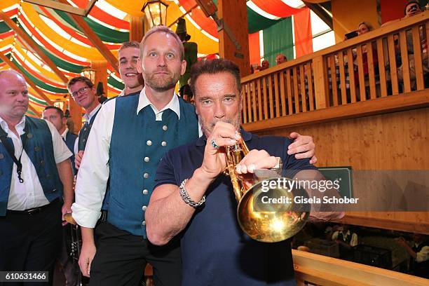 Arnold Schwarzenegger plays a trumpet during his visit of the Schuetzen Festzelt during the Oktoberfest at Theresienwiese on September 27, 2016 in...