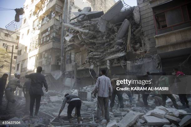 Syrian civilians and rescuers gather at site of government forces air strikes in the rebel held neighbourhood of Al-Shaar in Aleppo on September 27,...