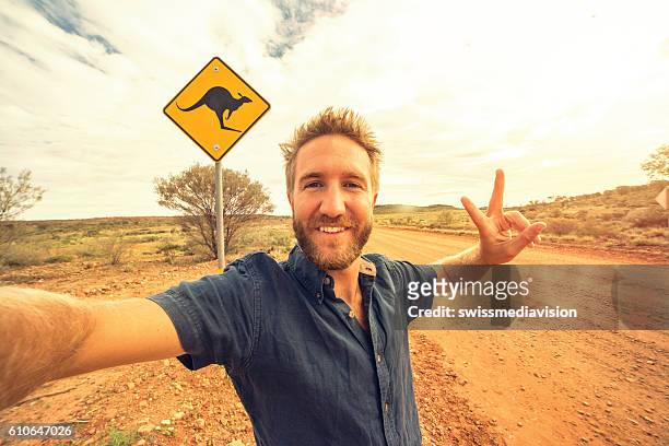 selfie of young man in australia standing near kangaroo sign - animal crossing sign stockfoto's en -beelden