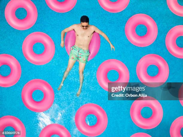 sorgloser mann am ring im schwimmbad - schwimmring stock-fotos und bilder