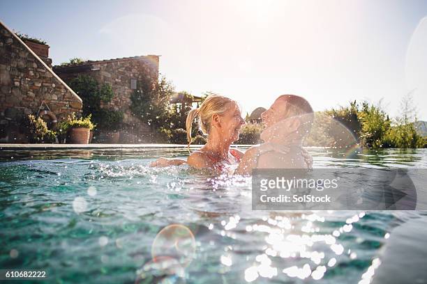 fun in the pool - couple laughing hugging stock pictures, royalty-free photos & images