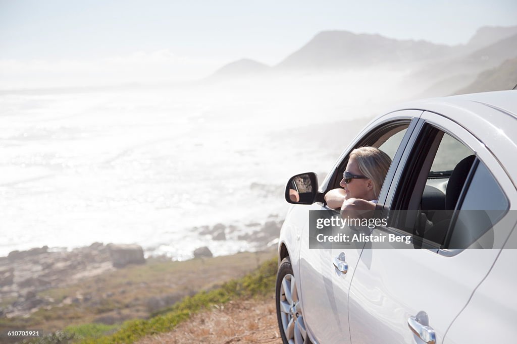 Woman looking out of car overlooking a beach