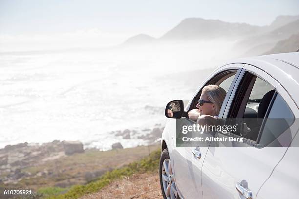 woman looking out of car overlooking a beach - car rental stock pictures, royalty-free photos & images
