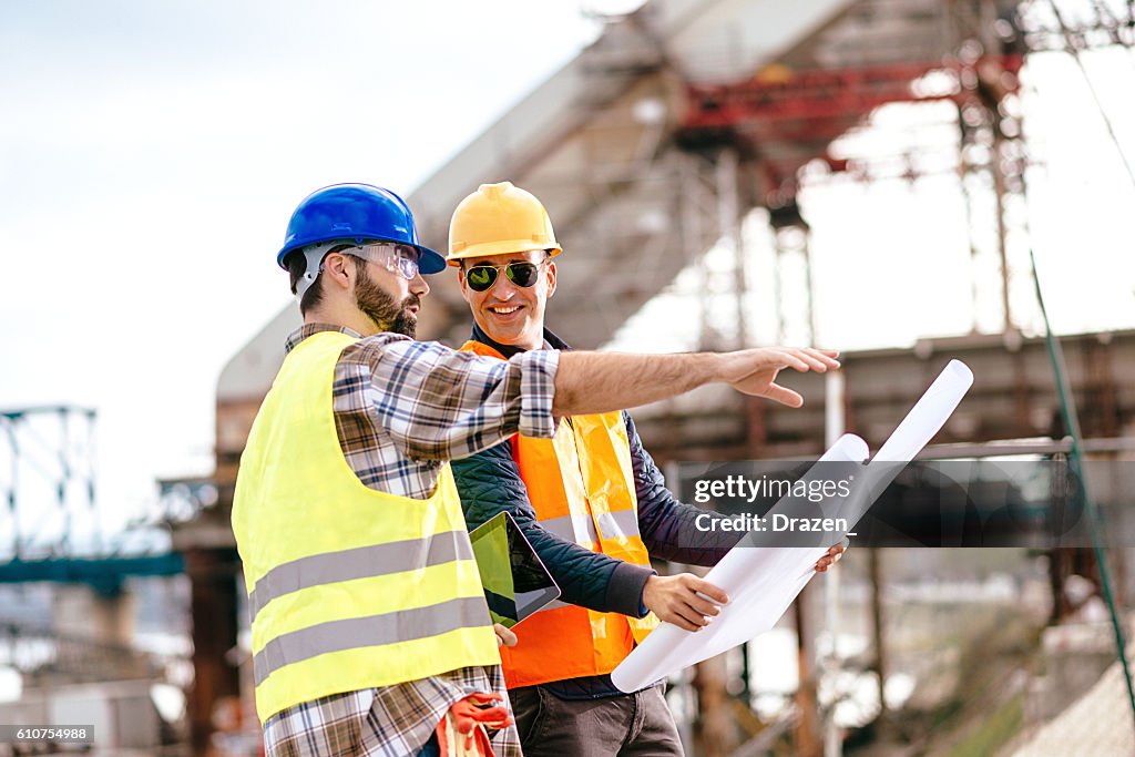 Experts having meeting on construction site and looking at blueprint