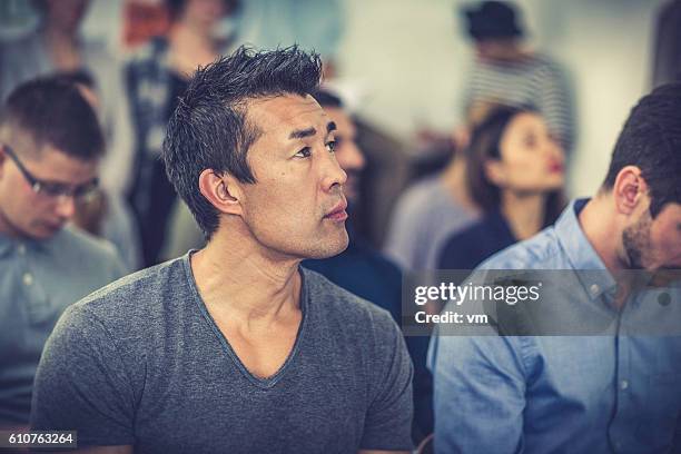 man of asian ethnicity listening closely to a presentation - looking closely stock pictures, royalty-free photos & images