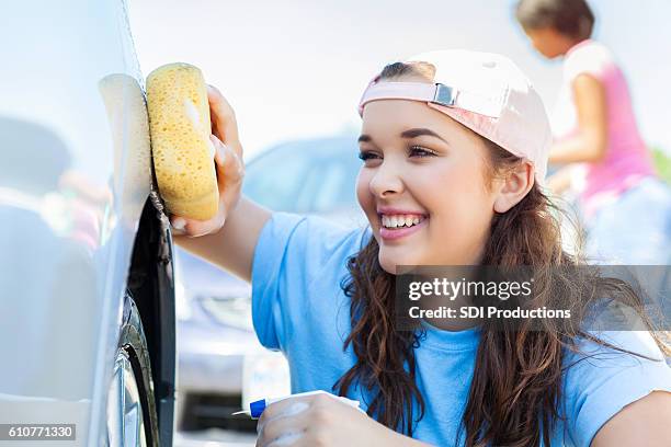 beautiful caucasian teenage smiles while washing a car - teen wash car stock pictures, royalty-free photos & images