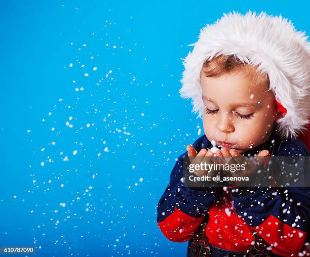 menino em santa chapéu de natal flocos de neve a soprarweather forecast - blowing a kiss imagens e fotografias de stock