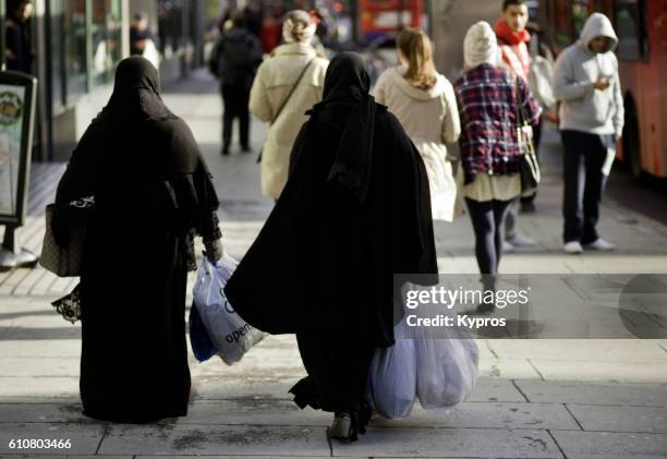 europe, uk, england, london, view of two muslim women wearing burka's cruising edgware road carrying plastic shooting bags - nikab stock-fotos und bilder