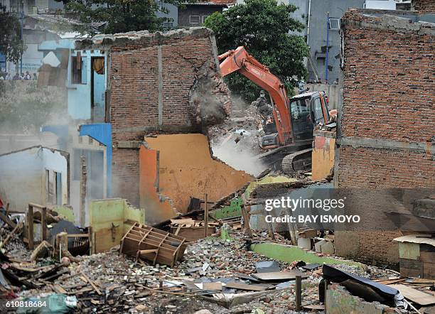 Digger destroys a wall during the demolition of over 300 settlements of the Bukit Duri neighbourhood located on the Ciliwung river banks, in order to...