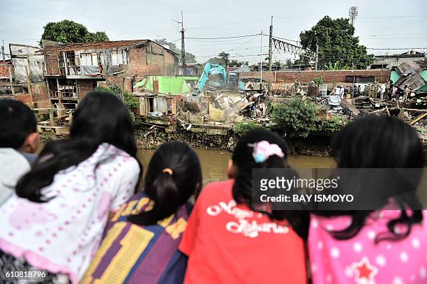 Girls watch the demolition of a home along with over 300 settlements of the Bukit Duri neighbourhood located on the Ciliwung river banks, in order to...
