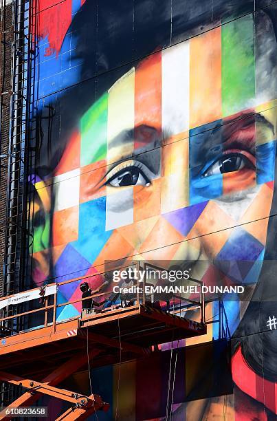 Brazilian street artist Eduardo Kobra and his assistant work on a large graffiti artwork of late writer Anne Frank at the shipyard at the NDSM...