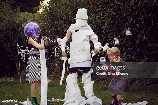 children playing halloween game - mummy stockfoto's en -beelden
