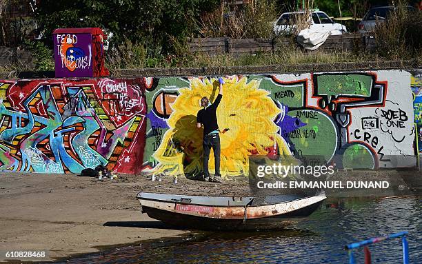 Street artist works at at the NDSM shipyards, in Amsterdam, on September 27, 2016. / AFP / EMMANUEL DUNAND / RESTRICTED TO EDITORIAL USE - TO...