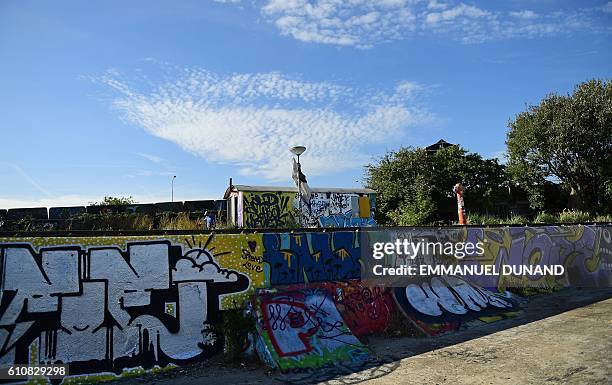 Person walks next to street artis's works at at the NDSM shipyards, in Amsterdam, on September 27, 2016. / AFP / EMMANUEL DUNAND / RESTRICTED TO...