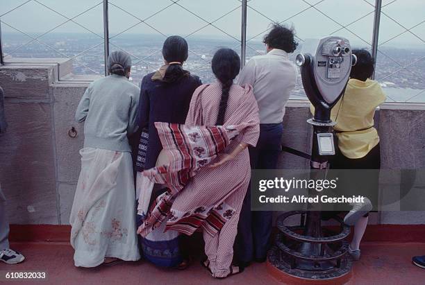 Group of Asian people looking out over Manhattan from the 86th floor observation deck of the Empire State Building, New York City, 1985.