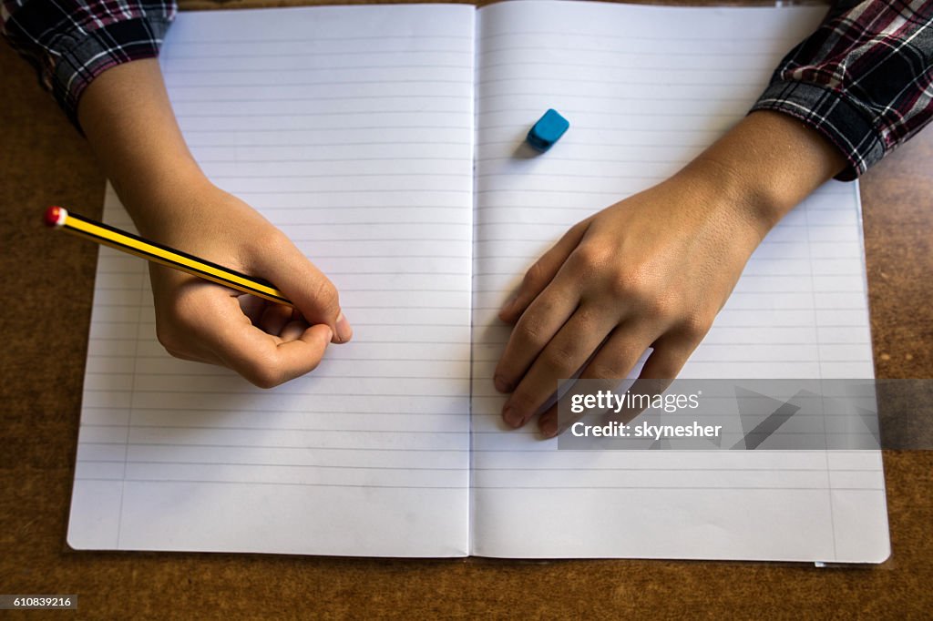 Above view of unrecognizable child writing into notepad.