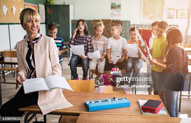 lächelnder musiklehrer mit einer gruppe von kindern im klassenzimmer. - gesangslehrer stock-fotos und bilder