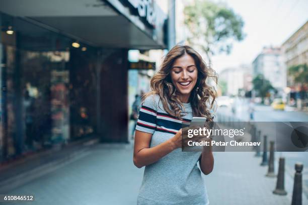 smiling girl texting on the street - attractive girl stockfoto's en -beelden