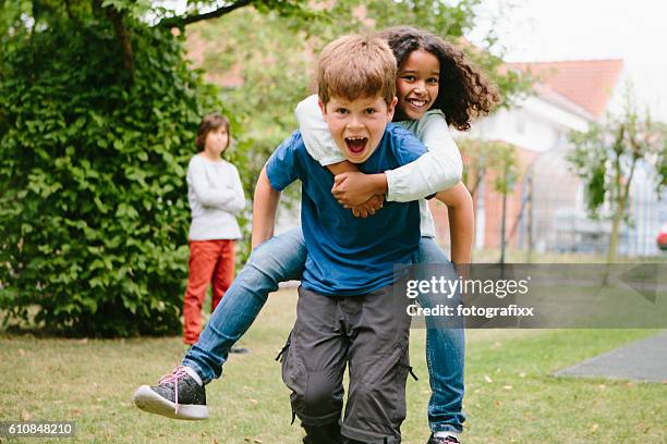 school children having fun with piggyback in schoolyard - piggyback stock pictures, royalty-free photos & images