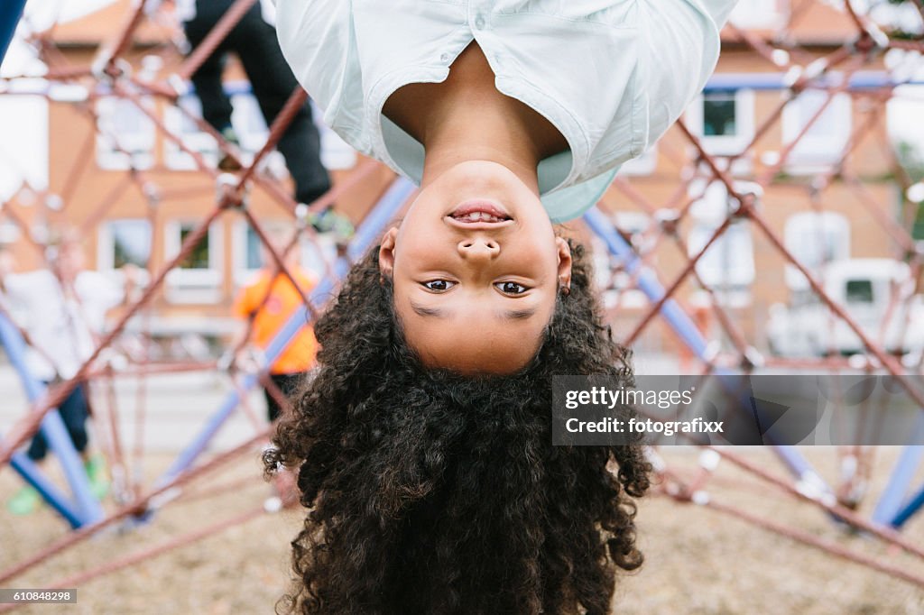 Outdoor portrait: cute schoolgirl at climber, looking at camera