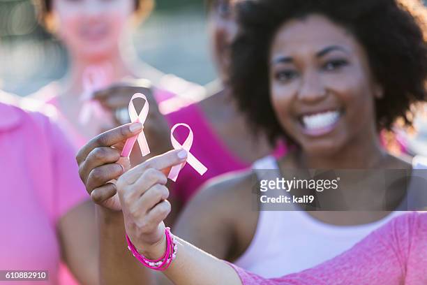 multiracial women holding breast cancer awareness ribbon - cancer ribbon stock pictures, royalty-free photos & images